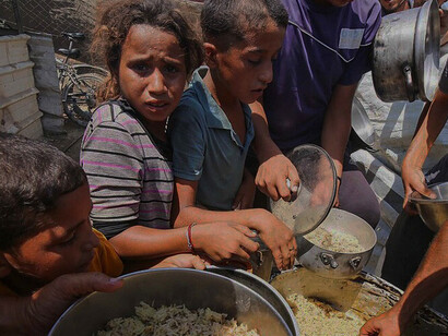 Palestinian families wait for food distributions provided by a charitable organization in Deir al-Balah, as humanitarian efforts continue to support vulnerable communities across Gaza