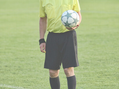 Arbitro con fischietto e pallone in mano