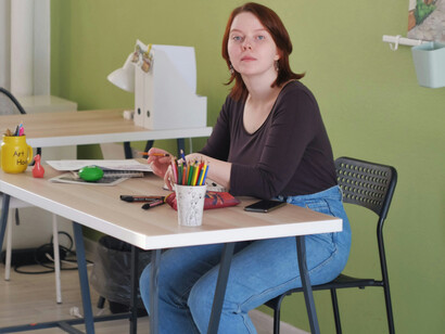 A young woman in a t-shirt and jeans sitting at her desk