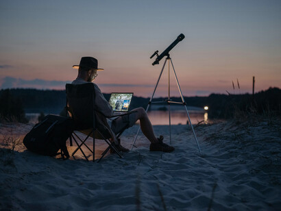 Un hombre con un telescopio y una computadora, analizando el espacio