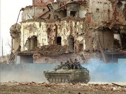 Tropas rusas pasan por edificios destruidos en Grozny el 13 de marzo de 1996