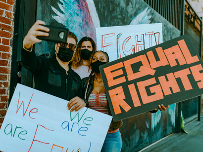 Protesters holding placards advocating equality and capturing the moment on their phones, representing the fusion of activism and digital visibility