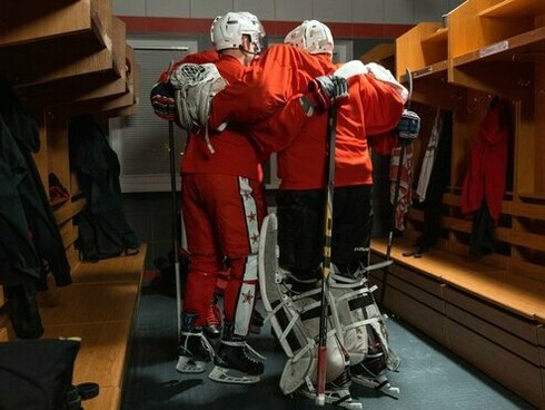 Hockey teammates standing shoulder to shoulder with their arms around one another, reflecting solidarity within a goal-oriented team
