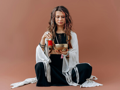 A woman in black and white playing a Tibetan bowl