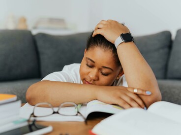 A female student rests her head in her hands, overwhelmed and burned out