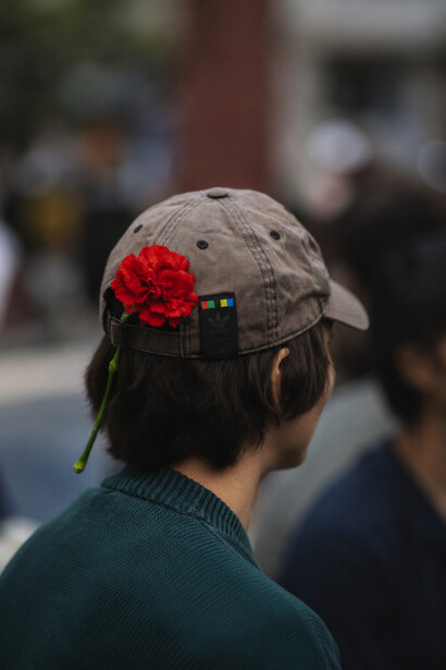 Retrato de costas destaca uma rosa presa ao boné de uma pessoa jovem. Entre expectativas e obstáculos, a juventude portuguesa surge como uma das mais afetadas pelas decisões discutidas no texto