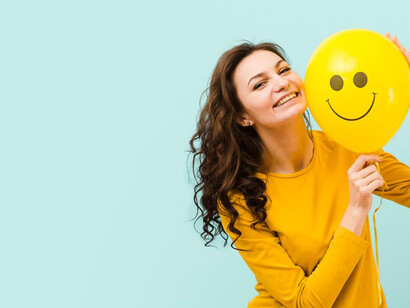 A woman holding balloons with smiley faces, symbolizing positive thinking and mental health
