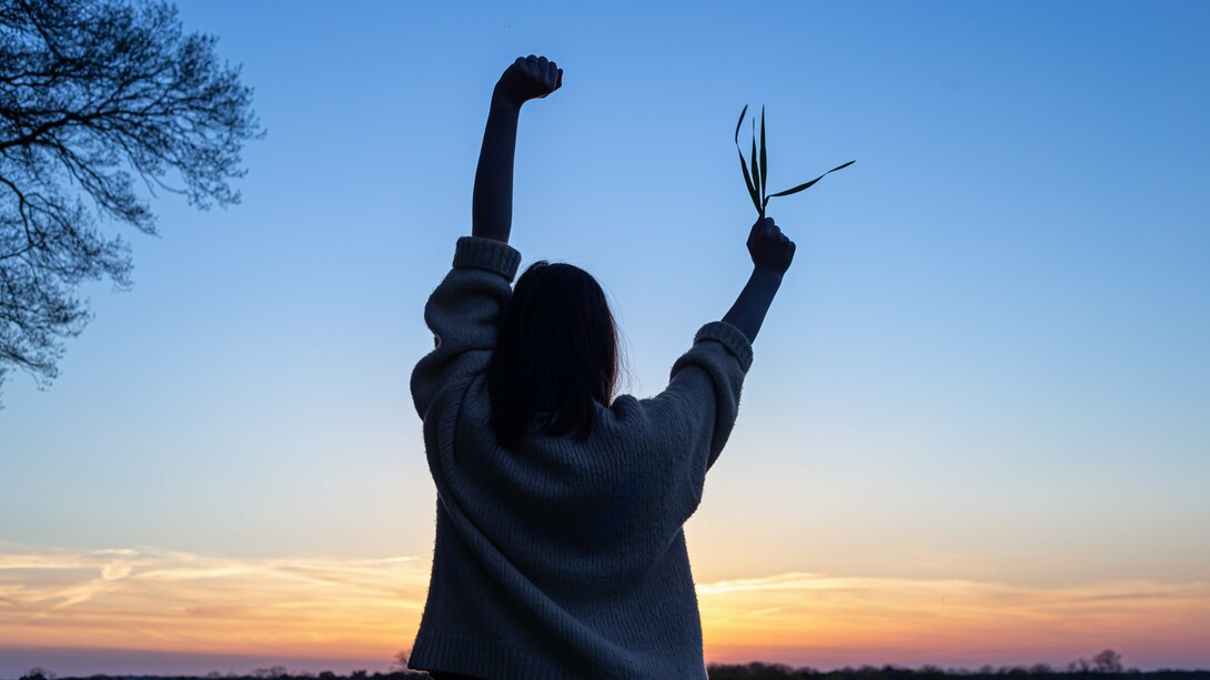 With arms raised in freedom and a sprig of life in hand, she embodies the power of simple, intentional choices to move, eat, and thrive toward a vibrant and healthy future