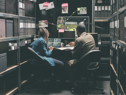 The shadowy realm of private investigation as detectives scrutinize surveillance photos on a laptop in a dimly lit room, uncovering the secrets shrouded in mystery