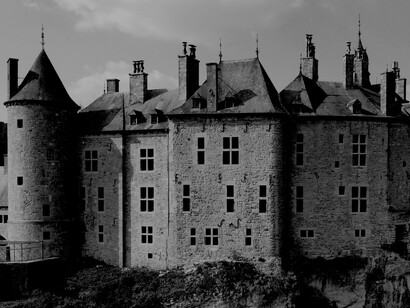 A grey Gothic-style concrete castle perched on a cliff in Belgium