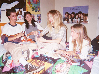 A 90s teenage bedroom with posters on the walls and friends hanging out