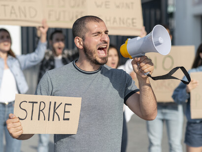 A young man holding a speaker at the picket line