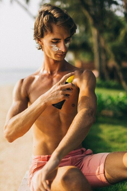 A person shielding their skin with sunscreen before enjoying the sunshine, reflecting the first line of defense against UV damage