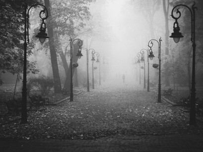 A misty, old cobbelstone road, flanked by several streetlamps