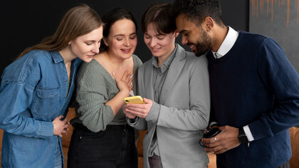 Friends engaging with a phone, exploring social media platforms and digital content creation, while discussing global political communication and the impact of Twitter diplomacy on digital public engagement