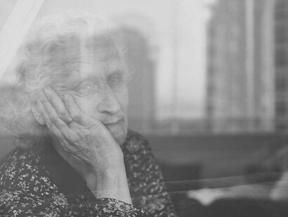 Mujer mayor solitaria mira por la ventana. La soledad es un problema de salud pública