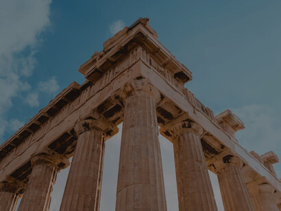 Captivating low-angle photography captures the majestic column ruins of an ancient temple in Athens, illuminated by the brilliant daylight