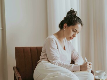 A woman journaling in a cozy apartment interior, focused on inner healing and relaxation