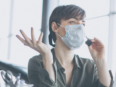 Amidst COVID-19 safety protocols, a woman is seen working in a recording studio, wearing a mask while operating a computer, highlighting the integration of digital technology in the workplace during the pandemic