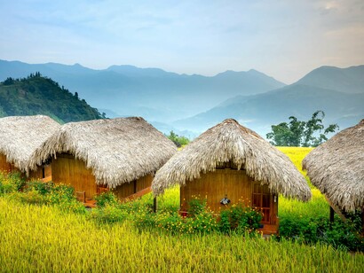 A cluster of bamboo homes set amid farmland, representing sustainable living grounded in local materials