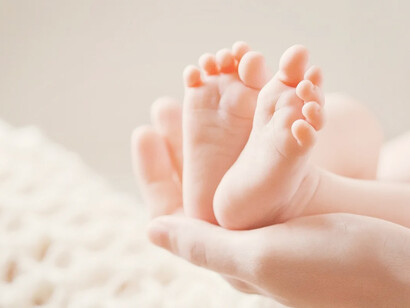 Manos de adulto sosteniendo los pies de un bebé