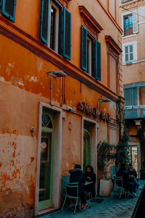 A group of diners enjoying a relaxed evening at a cozy street restaurant in Rome, Italy, immersed in the lively atmosphere of outdoor Italian dining