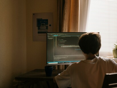 A boy sat at a desk using a computer screen