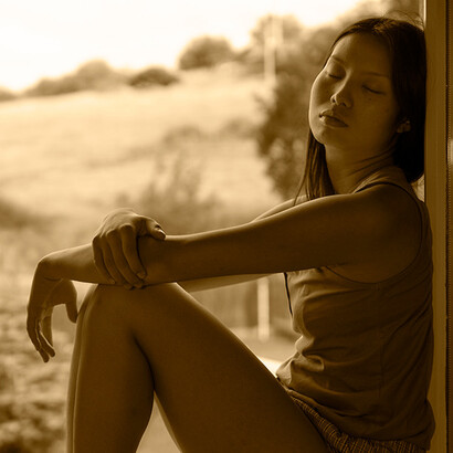 Mulher em janela. Uma brisa suave anunciou o fim do verão, o sol afundou-se na linha do horizonte, mas a escuridão ainda não caiu totalmente, o tom pastel da luz ainda deixa adivinhar pormenores da paisagem