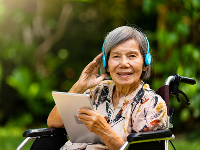 Listening to cherished songs on a tablet, an older woman experiences the therapeutic benefits of music, where familiar tunes can awaken memories and emotional connections