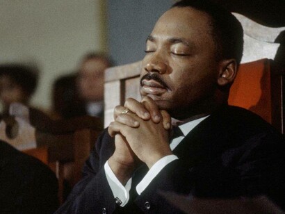 Martin Luther King Jr. praying in a church in the United States for peace and justice