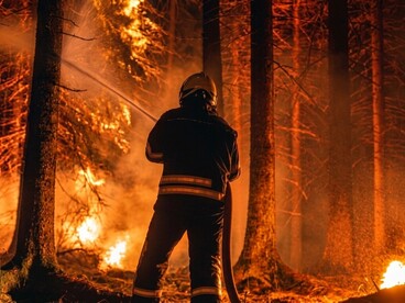 Firefighters working to contain a massive wildfire with high-pressure water hoses