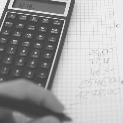 A person diligently crunching numbers on a calculator to meticulously calculate their budget