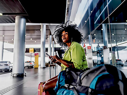 A mid-adult woman waits calmly for a taxi outside the airport terminal