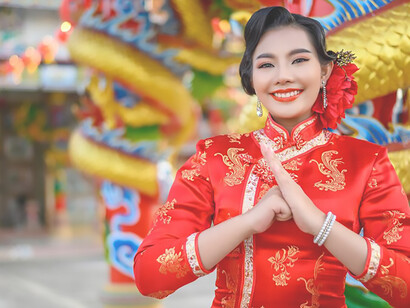 Embrace the spirit of the Year of the Dragon as the smiling woman poses amidst vibrant Lunar New Year decorations, symbolizing luck and renewal