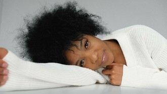A woman laying down and proudly displaying her culture and heritage with her black hairstyle