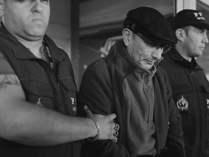 Following his extradition from France, Mario Sandoval, a former police officer charged with crimes from Argentina's "dirty war," is seen being escorted by police at Ministro Pistarini International Airport in Buenos Aires on December 16, 2019