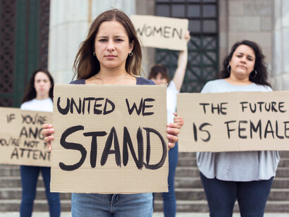Women standing united with messages of empowerment, representing the confidence that fuels future leadership