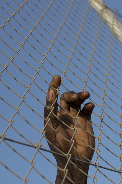 Uma mao dum imigrante subsaariano na vedação de Melilla