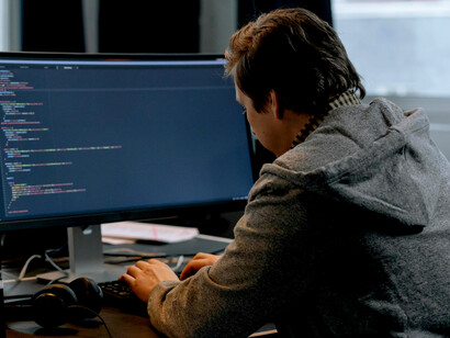 A software developer working on HTML code on a laptop in an office settin