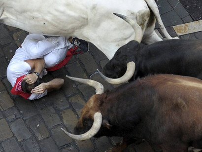 Fiestas de San Fermín en Pamplona. Un mozo cae al suelo ante los toros