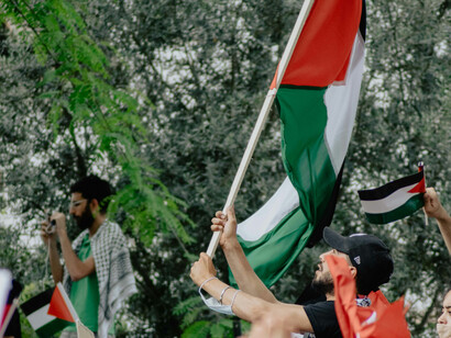 Several people wave Palestinian flags at a rally