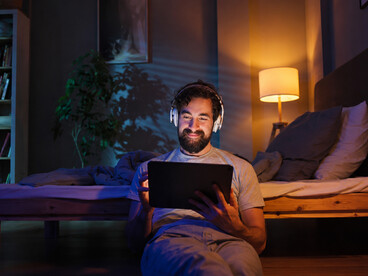 Relaxed young man enjoying a movie on his tablet with headphones on