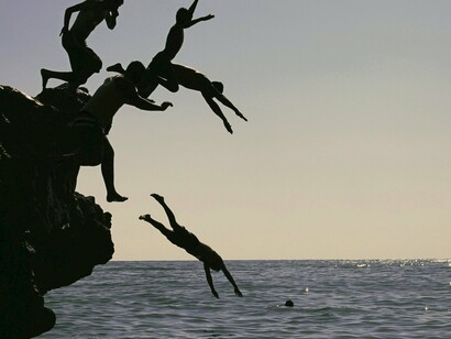 Pessoas felizes em pôr-do-sol na praia. Aristóteles criticou o idealismo do mestre, “reconhecendo a necessidade de elementos básicos, como a boa saúde, a liberdade (em vez da escravidão) e uma boa situação socioeconômica para alguém ser feliz”. E ambos defendiam que era função do Estado tornar os homens felizes