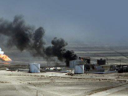 Oil wells burn out of control, darkening the sky with smoke, after being set ablaze by retreating Iraqi forces during Operation Desert Storm