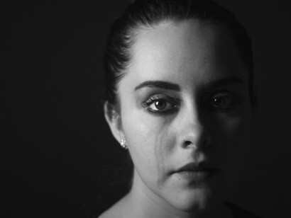 Una mujer víctima de violencia de género llorando, mira desafiantemente. Muchas mujeres se alzan contra la violencia