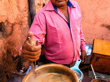 Portrait of an Indian street vendor preparing and serving chai tea
