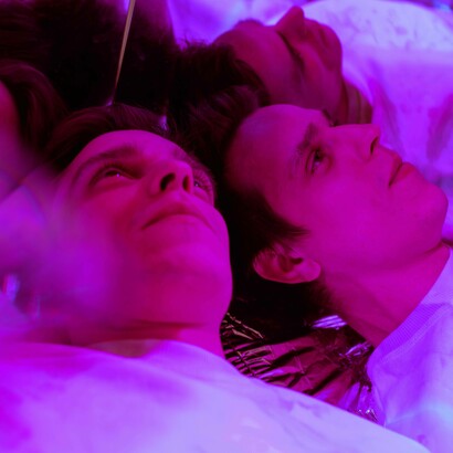 Multi riflesso di un uomo sdraiato, illuminato da una forte luce viola e magenta