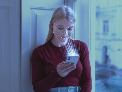 A woman uses facial recognition on her phone, illustrating how everyday interactions now demand comfort with rapidly evolving technologies