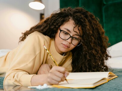 Woman relaxing on her bed as she writes in a notebook