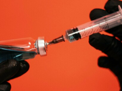 Pessoa coleta solução líquida com uma seringa. Embora a tecnologia seja considerada segura e eficaz, a rapidez do desenvolvimento e a falta de estudos de longo prazo levantaram questões sobre possíveis efeitos secundários que poderiam se manifestar após meses ou anos
